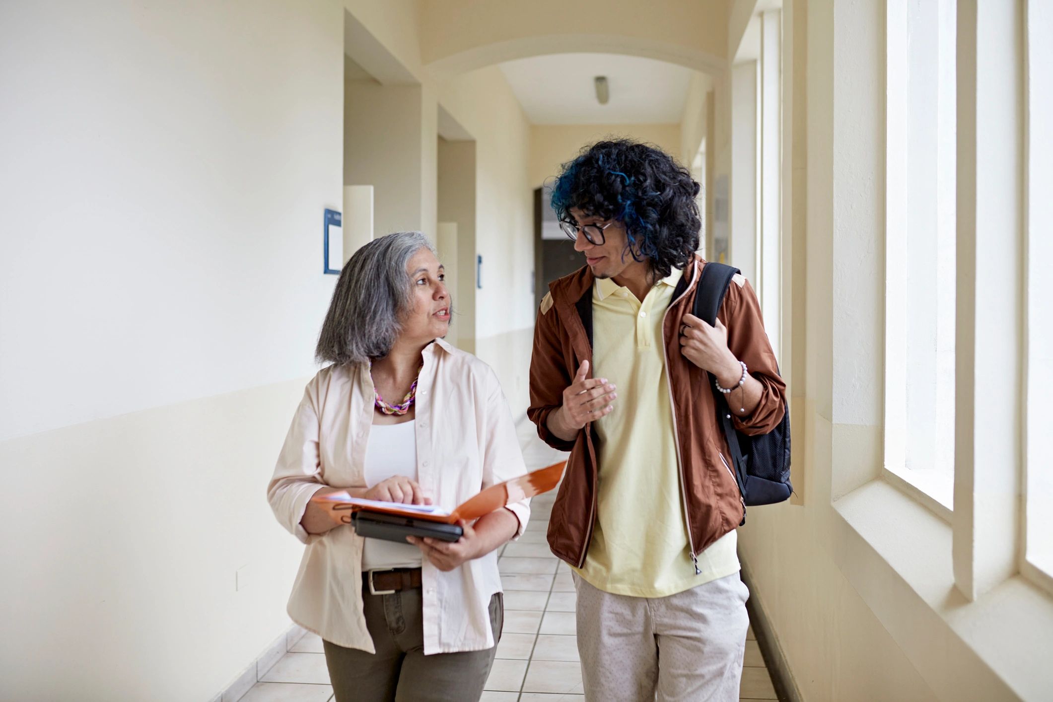 Mentor and student walking and talking on campus
